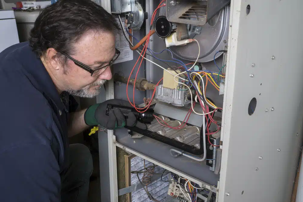 An HVAC technician doing a maintenance check on an old furnace.