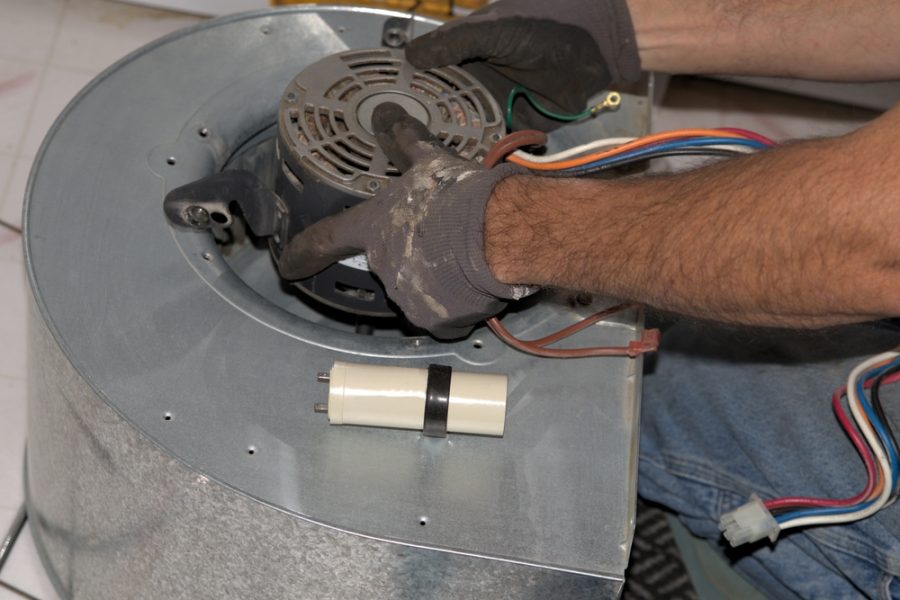 An HVAC technician is fixing a furnace blower motor.