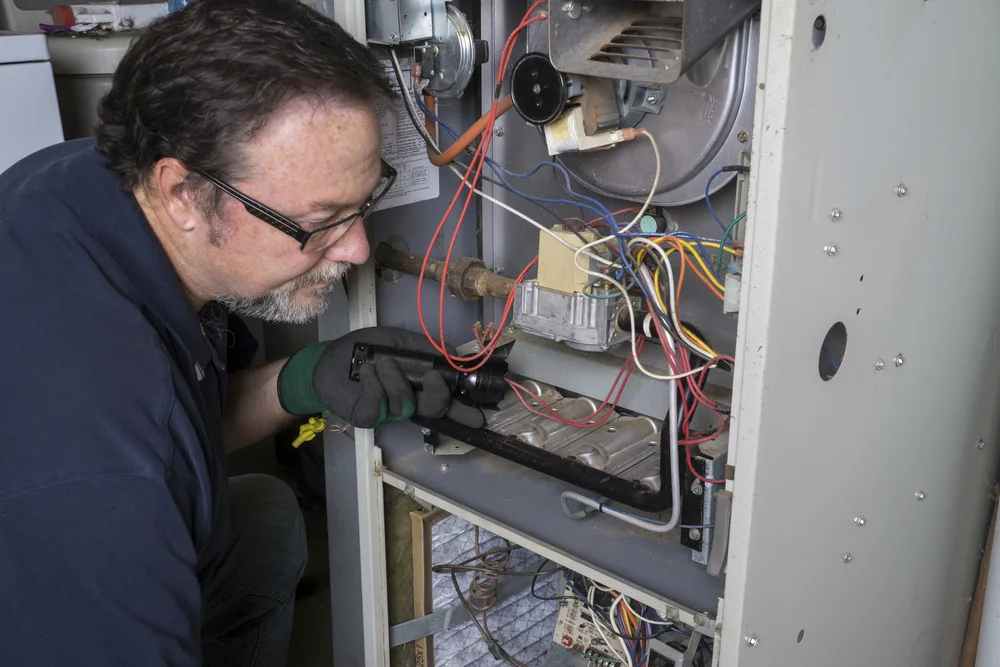 An HVAC expert is checking the furnace blower motor.