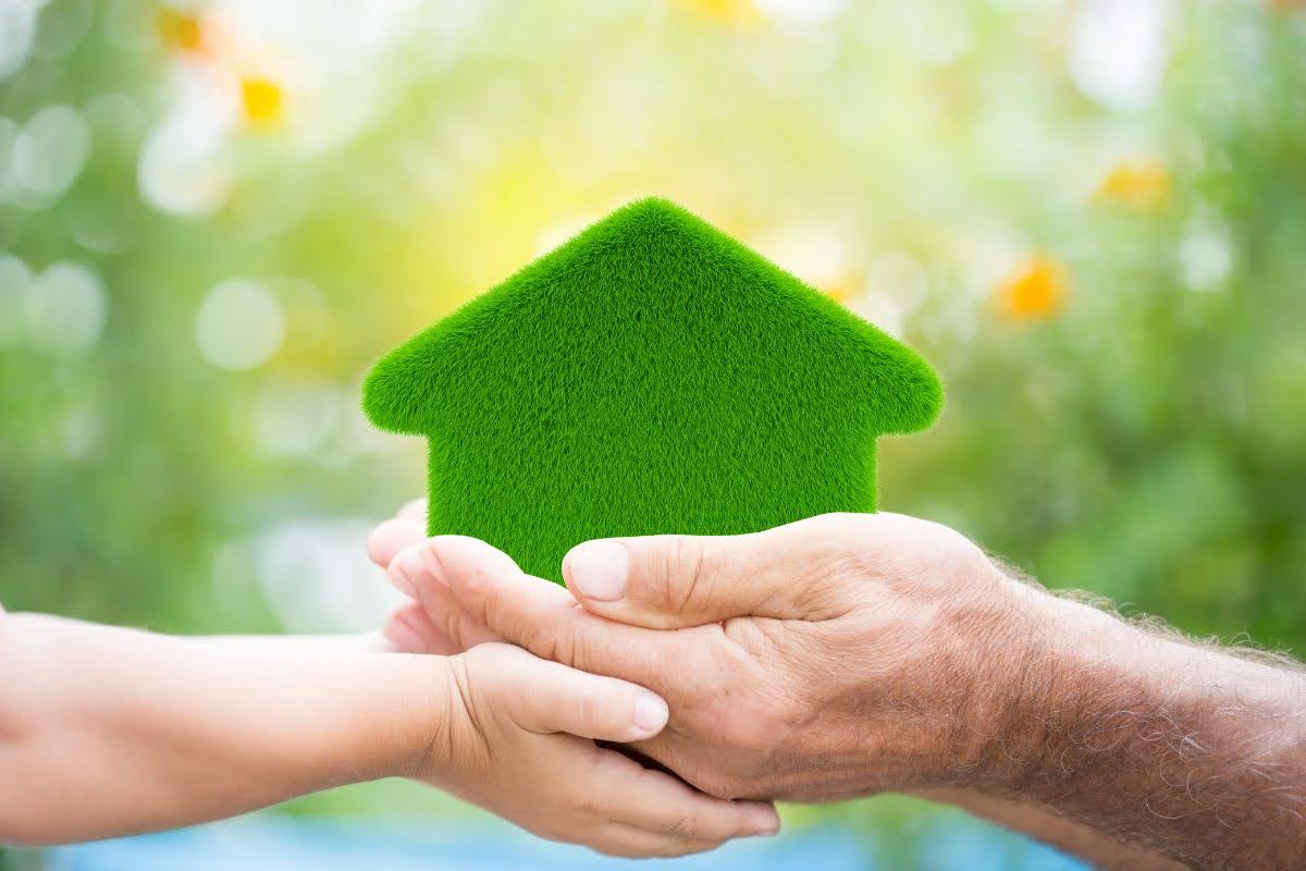 A child holding a green house, symbolizing eco-friendly HVAC solutions for a sustainable future.