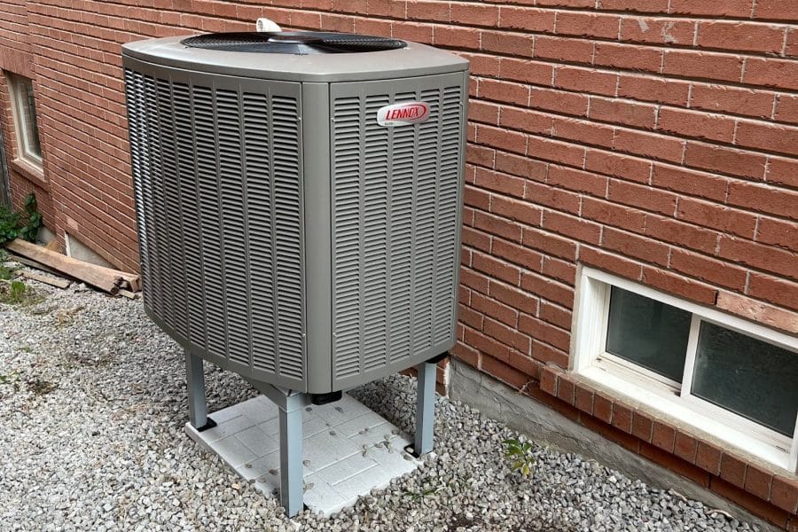 A Lennox heat pump elevated from the ground.