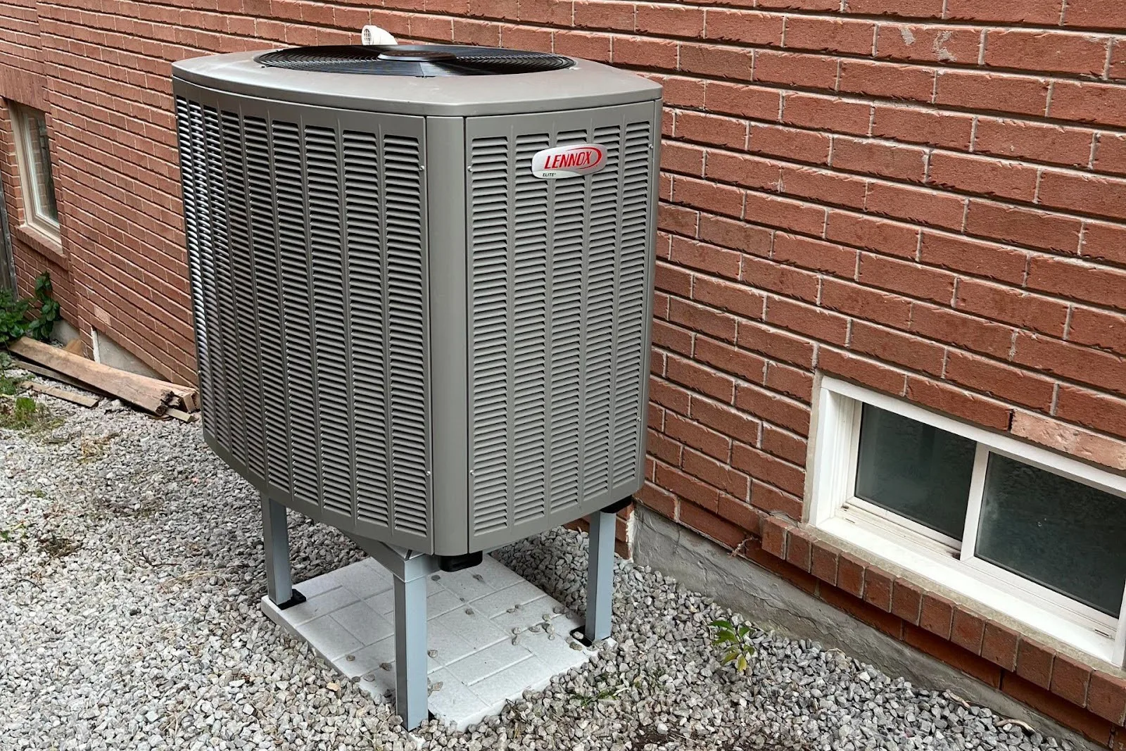 A Lennox heat pump elevated from the ground.
