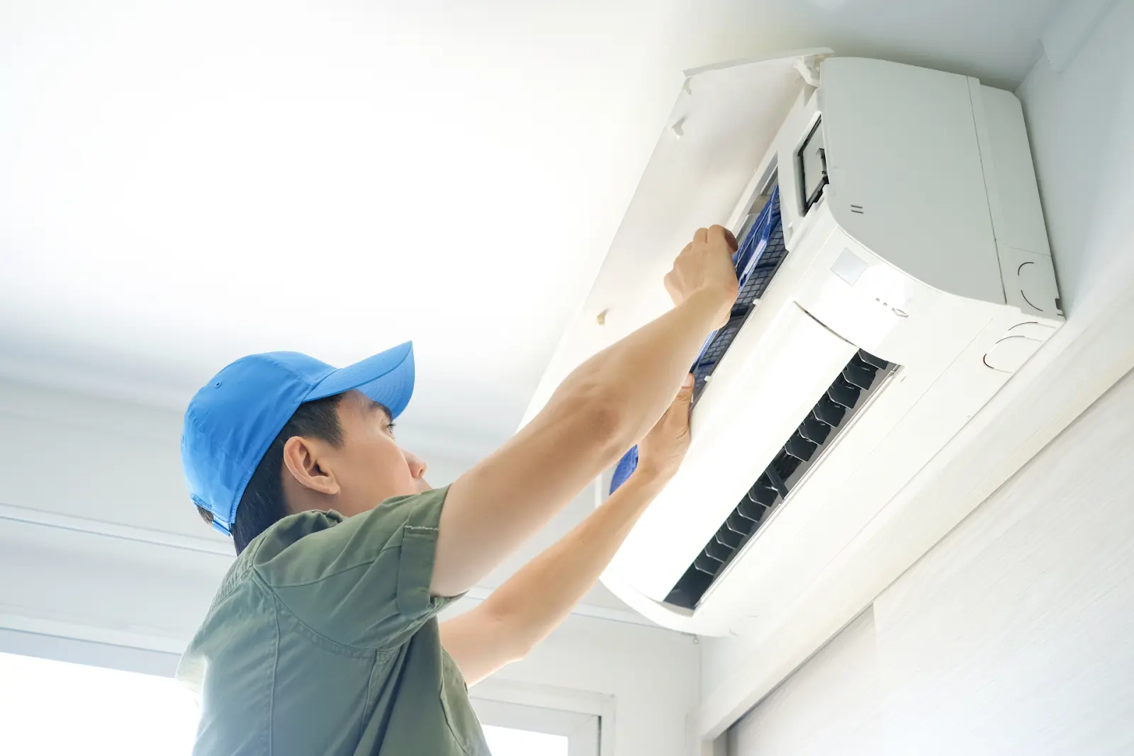 A homeowner changing the air filter in his mini-split air conditioner.