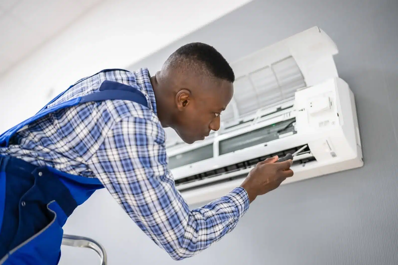 An HVAC technician is installing the indoor ductless AC unit.