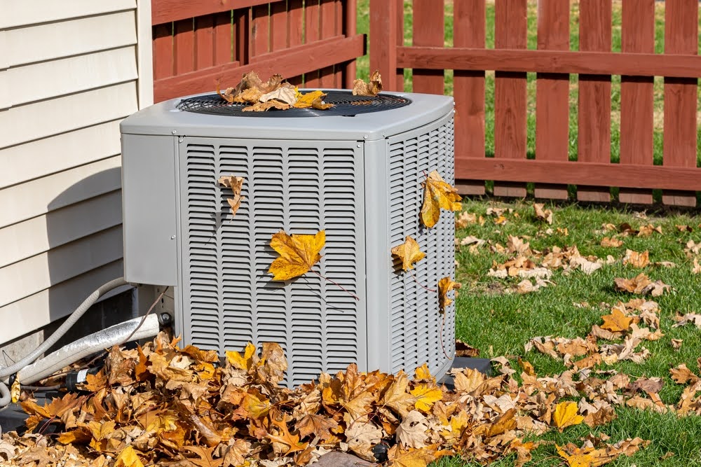 An outside AC unit covered with leaves.